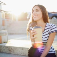 young woman sitting on stairs outdoors and holding coffee - junk food stock pictures, royalty-free photos & images