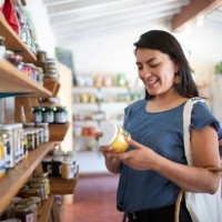 young woman smiling buying healthy, artisanal food at small local store - food stock pictures, royalty-free photos & images