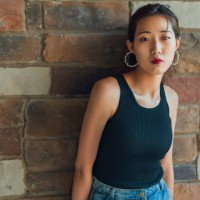 young woman standing in front of a stone wall - fashion stock pictures, royalty-free photos & images