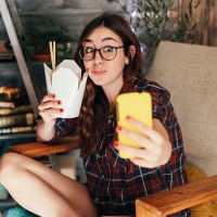 young woman taking a selfie with her chinese takeaways. - junk food stock pictures, royalty-free photos & images