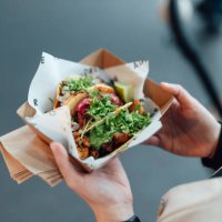 young woman taking lunch break and enjoying tacos in street food market - junk food stock pictures, royalty-free photos & images