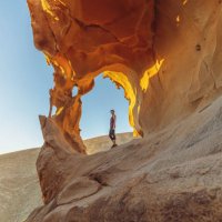 young woman under a natural rock arch in the fuerteventura desert at sunset - travel stock pictures, royalty-free photos & images
