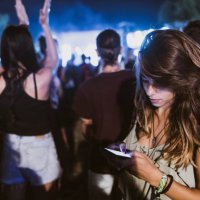 young woman using cell phone on music concert by night. - concert stock pictures, royalty-free photos & images