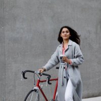 young woman walking with bicycle, with reusable coffee cup in hand - junk food stock pictures, royalty-free photos & images