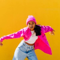 young woman wearing knit hat dancing in front of yellow wall - fashion stock pictures, royalty-free photos & images