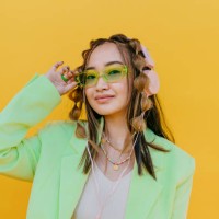 young woman wearing sunglasses and listening music through headphones in studio - fashion stock-fotos und bilder