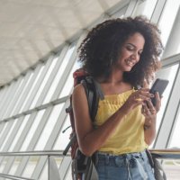 young woman with backpack checking her boarding schedule at the airport - travel stock pictures, royalty-free photos & images