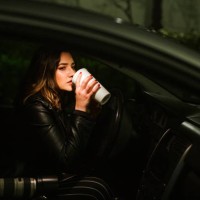 young woman with disposable cup and camera in a car at night - junk food stock pictures, royalty-free photos & images