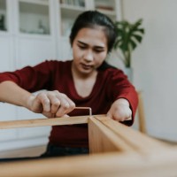 young woman with hand disability installing a wooden shelf by herself. - home decoration stock pictures, royalty-free photos & images