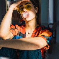 young woman with head in hand blowing bubble gum at home - fashion stock-fotos und bilder
