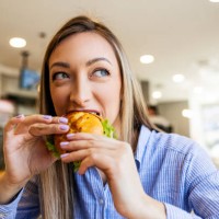 young women eating sandwich looking through window - junk food stock pictures, royalty-free photos & images