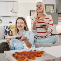young women watching favorite tv show and eating pizza - junk food stock pictures, royalty-free photos & images