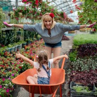 young women working together with their little daughter in a flower garden showing her family business - garden decoration stock pictures, royalty-free photos & images