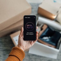 your order has been shipped - close up shot of hand holding smartphone with online shopping box stack at the background - fashion stock pictures, royalty-free photos & images