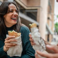 youth enjoy tasty street food while laughing and socializing in the vibrant streets of sydney, australia during the weekend - junk food stock pictures, royalty-free photos & images