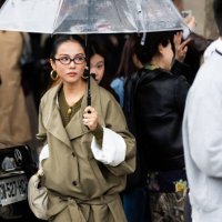 Yoyo Cao wears a leather beige bag, brown glasses, gold hoop earrings, a military green sweater and an olive green short coat outside Chloé show...
