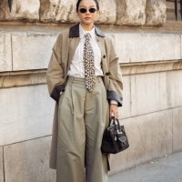 Yoyo Cao wears black sunglasses, a leopard printed tie, a white and beige striped shirt, a black leather Birkin Hermès bag, a beige long trench coat...