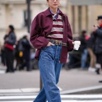 Yoyo Cao wears golden earrings, a burgundy oversized jacket , a striped polo shirt, a belt, blue denim pants / jeans , brown leather loafers shoes,...