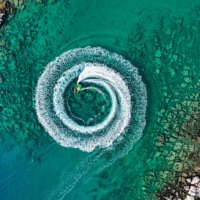zoom out amazing aerial view of man driving a personal watercraft in the ocean creating a straight down circular pattern,amazing summer background, water color and beautiful bright clear turquoise adventure day on tropical be
