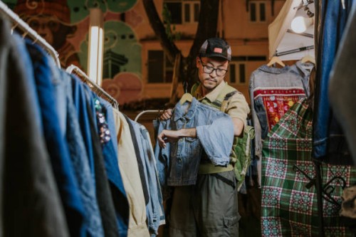 2nd hand jeans market, asian tourist man is interesting in a jacket. - fashion stock pictures, royalty-free photos & images