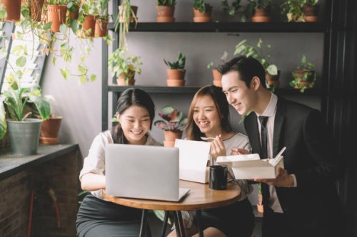 3 asian chinese office executive having lunch break at their cafeteria in office during noon with their lunch box and looking at laptop - junk food stock pictures, royalty-free photos & images