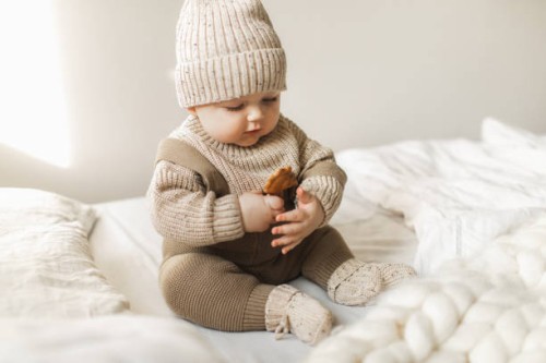 a 5 month old baby boy in cotton knitwear laying on a bed. - fashion stock pictures, royalty-free photos & images