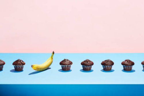 a banana in a row of chocolate cupcakes - junk food stock pictures, royalty-free photos & images