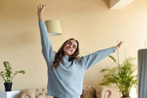 a beautiful girl in a blue sweater is stretching in the room. - fashion stock pictures, royalty-free photos & images
