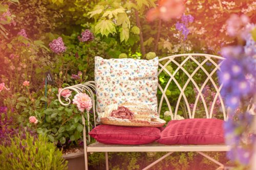 a beautiful summer cast iron garden chair with cushions and a summer hat, shabby chic scene - garden decoration stock pictures, royalty-free photos & images