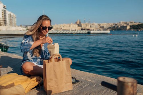 a beautiful woman enjoys eating noodles and relaxing by the sea - junk food stock pictures, royalty-free photos & images