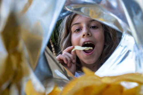 a boy eating chips from a package. - junk food stock pictures, royalty-free photos & images