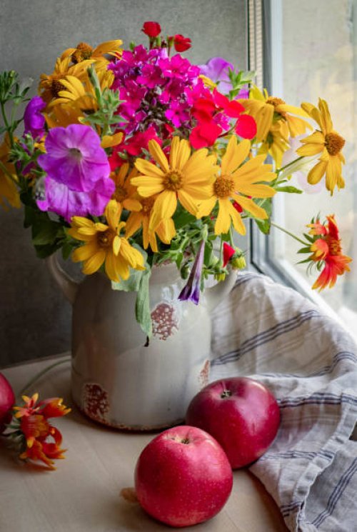 a bright bouquet of flowers in a ceramic vase and red ripe apples. - garden decoration stock pictures, royalty-free photos & images