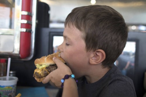 a child eats a burger - junk food stock pictures, royalty-free photos & images