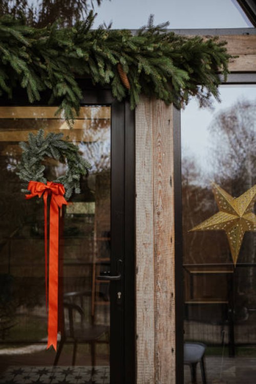a christmas wreath and pine branches hanging on a house outside - home decoration stockfoto's en -beelden