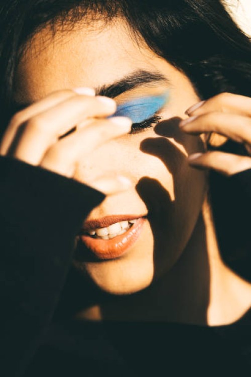 a conceptual fashionable portrait of a woman with bright blue eyeshadow against the sun - fashion stock pictures, royalty-free photos & images