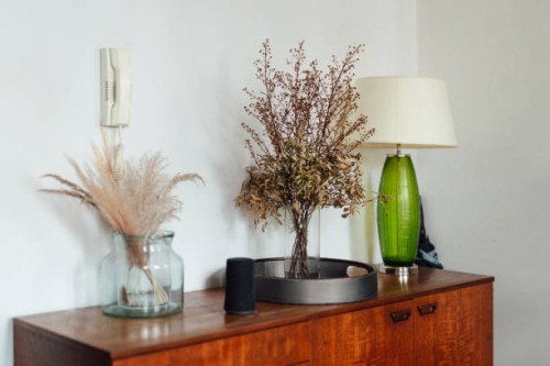 a corner of the living room - a retro style table lamp and some preserved flowers in vase on a wooden sideboard - home decoration stock pictures, royalty-free photos & images