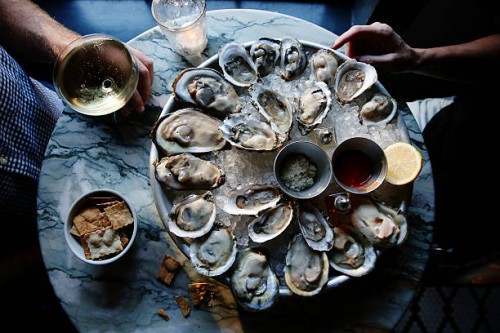 a couple enjoying raw oysters - food stockfoto's en -beelden