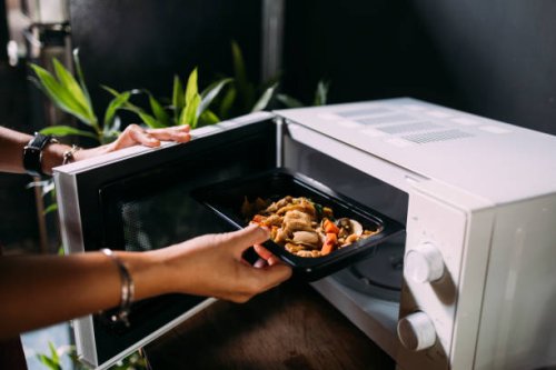 a cropped photo of an anonymous caucasian female heating food in the oven - junk food stock pictures, royalty-free photos & images