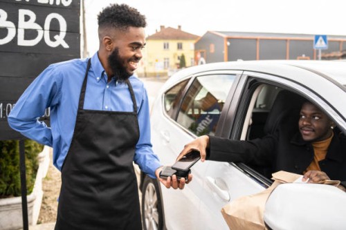 a customer paying by contactless technology while collecting his curbside delivery of take away food - junk food stock pictures, royalty-free photos & images