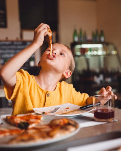 a cute girl eats pizza with an appetite, stretching the cheese. - junk food stock pictures, royalty-free photos & images