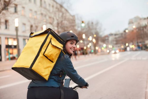 a delivery biker looking over their shoulder. - food stock pictures, royalty-free photos & images