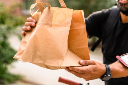 a delivery man is using a bike to transport food in the city - junk food stock pictures, royalty-free photos & images