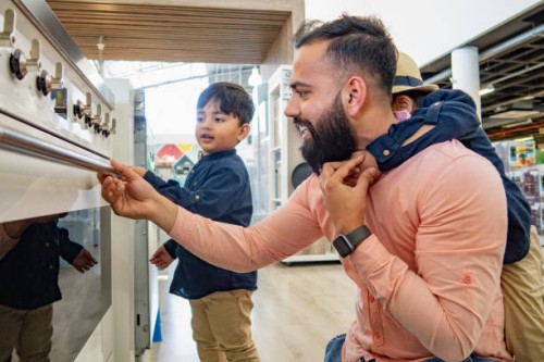 a father and two sons looking at ovens in an appliance store. - home decoration stock pictures, royalty-free photos & images
