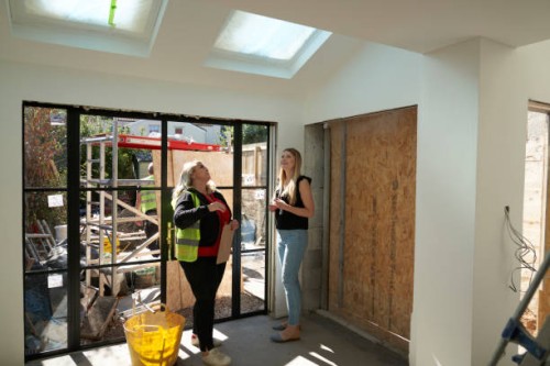 a female builder stands in a building site amongst a half finished renovation discussing the project with her client. - home decoration stock pictures, royalty-free photos & images