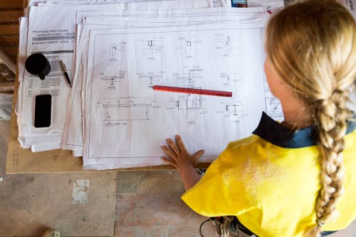 a female construction worker looks at site plans - home decoration fotografías e imágenes de stock
