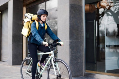 a female delivery person standing in front of a doorway. - junk food stock pictures, royalty-free photos & images
