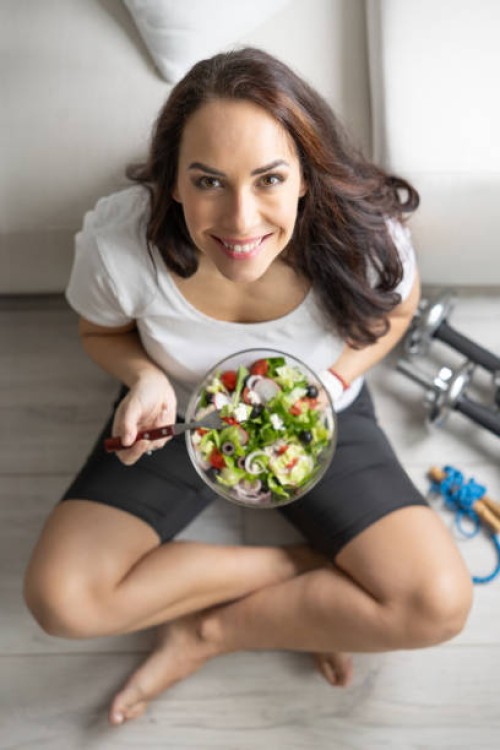 a fit woman in her forties eating a healthy salad after exercise. concept of healthy lifestyle. - food stock pictures, royalty-free photos & images