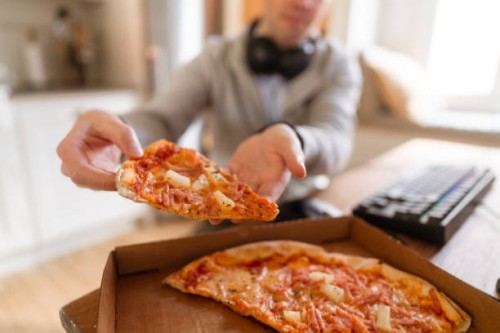a gamer eating pizza out of the box, sitting in front of his computer - junk food stock pictures, royalty-free photos & images
