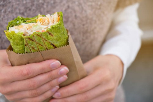 a girl eats a vegetarian vegetable shawarma on the street. fast food. lavash, burrito, roll in the hands of a woman. - junk food stock pictures, royalty-free photos & images