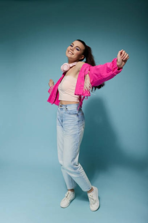 a girl in bright clothes with headphones and bright makeup jumps and smiles on a colored background in the studio - fashion stock pictures, royalty-free photos & images